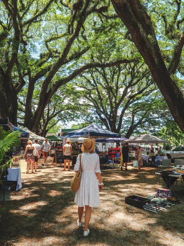 a woman walking through Mossman Markets 