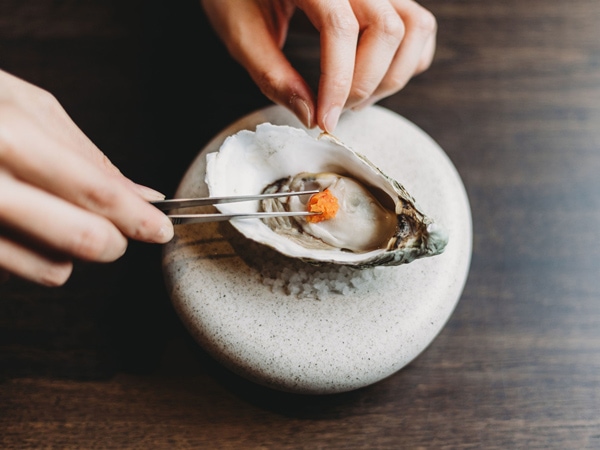 a person preparing a plate of seafood at Mu, Canberra