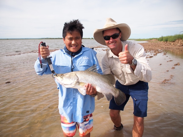 two men smiling while holding a freshly caught barramundi, Heli Fishing Adventures