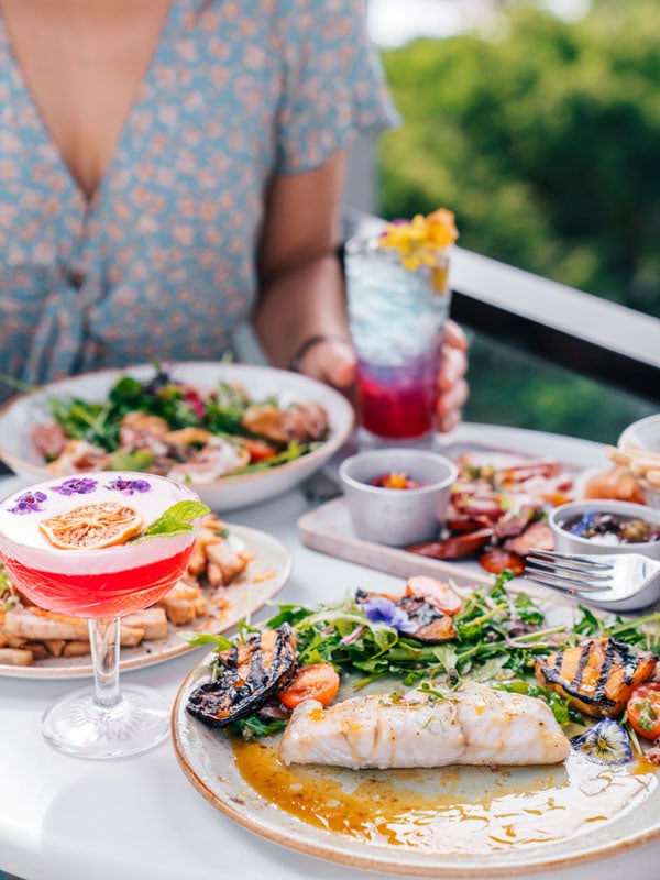 a woman enjoying food and drinks at the rooftop Oak & Vine restaurant