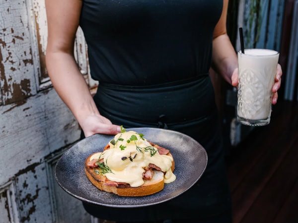 a woman holding a drink and breakfast plate at The Three Monkeys, Newcastle