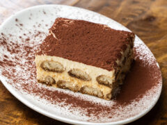 A piece of tiramisu on a white plate.