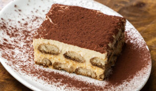 A piece of tiramisu on a white plate.