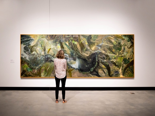 a visitor at HOTA admiring William Robinson’s The Rainforest artwork