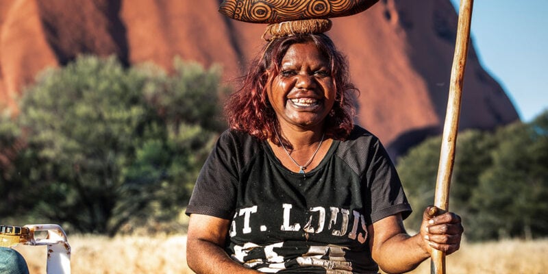 indigenous artists in front of uluru with Maruku Arts