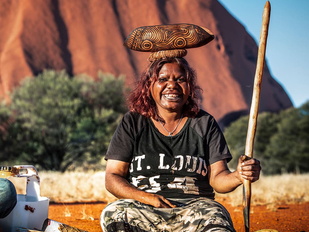 indigenous artists in front of uluru with Maruku Arts