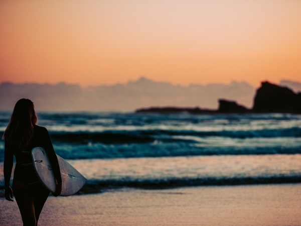 a girl heading to surf on the Gold Coast beach