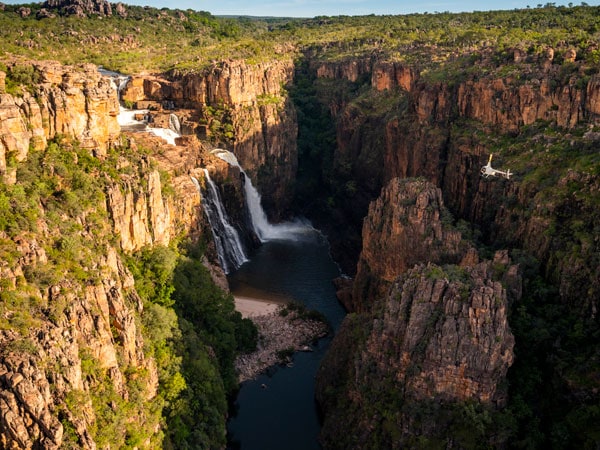 a helicopter hovering above Twin Falls and Jim Jim Falls in Kakadu National Park