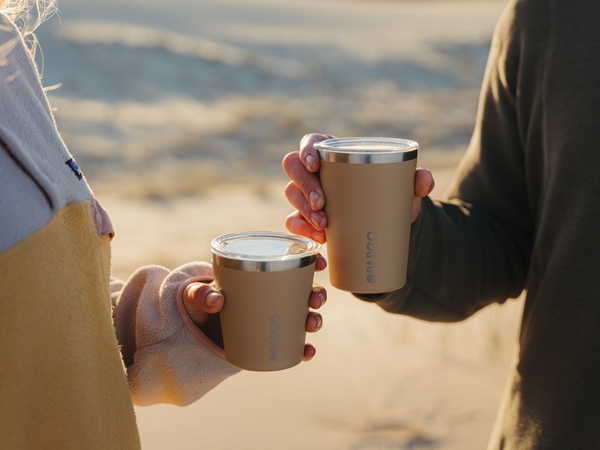 two people holding Project Pargo coffee cups in the desert