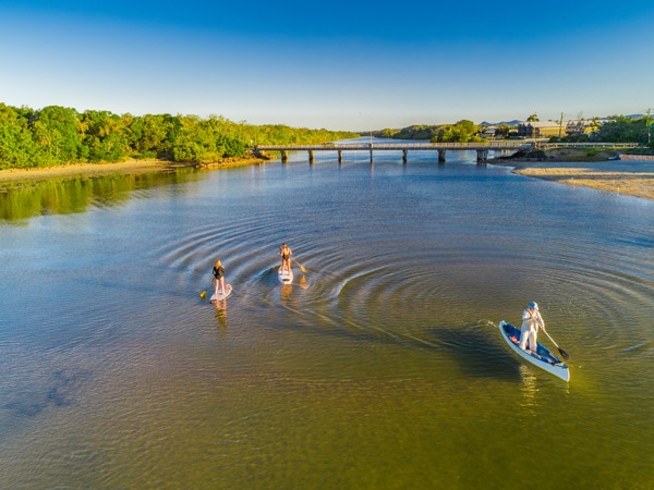 an aerial view of people paddle-boarding at Boyds Bay in Tweed Holiday Parks, Pottsville South
