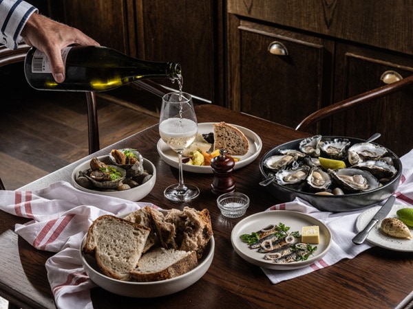 pouring wine into the glass with food on the table at The Rover, Surry Hills