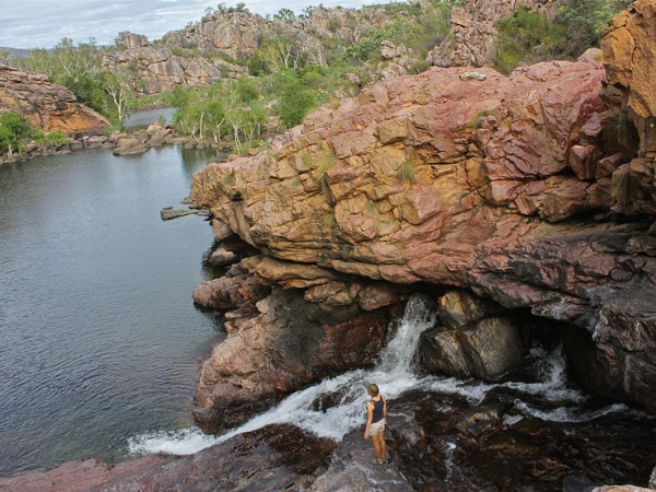 a woman surrounded by waterfalls and rocky ridges at Koolpin Gorge