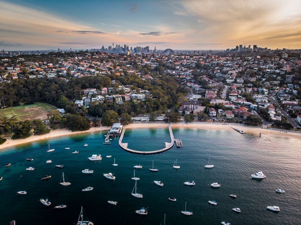 Balmoral Beach and Baths from above with views of Sydney skyline in the background