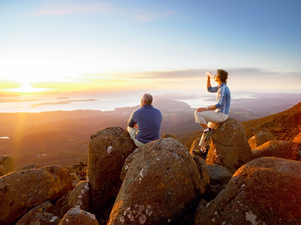 two people atop the summit of Mt Wellington at. sunset