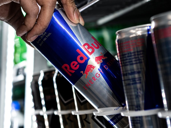 a hand grabbing a can of Red Bull
