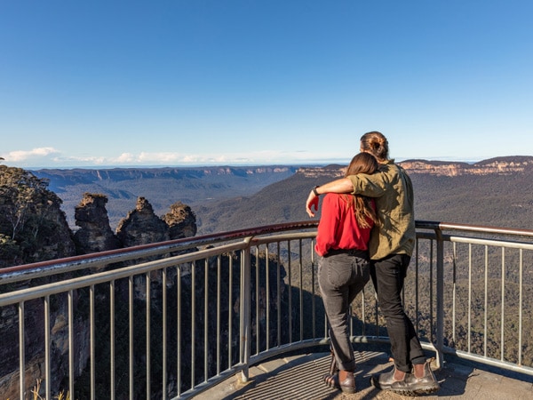 a couple admiring the Three Sisters view from Echo Point Lookout in the Blue Mountains