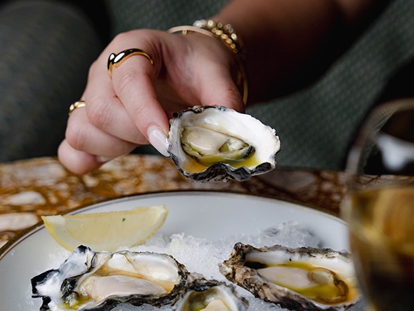 A woman trying an oyster at Bar Lucia