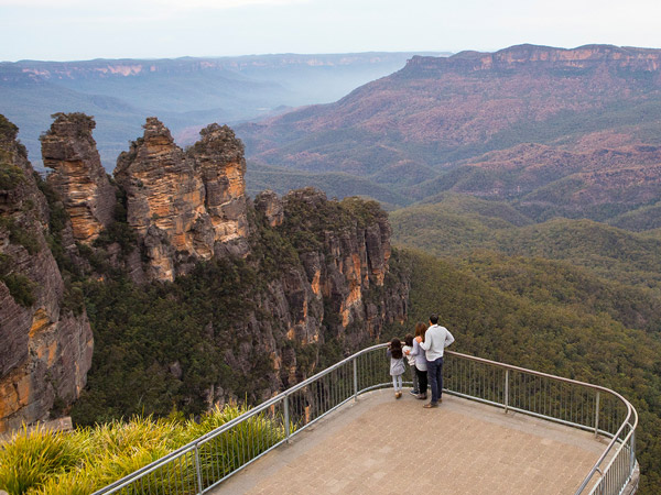 a family enjoying views of Three Sisters and Mount Solitary from Echo Point Lookout