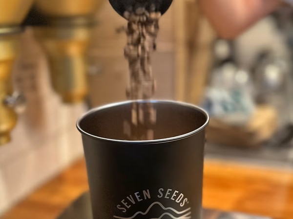 a close-up shot of coffee beans pouring into the cup, Seven Seeds Coffee Roasters