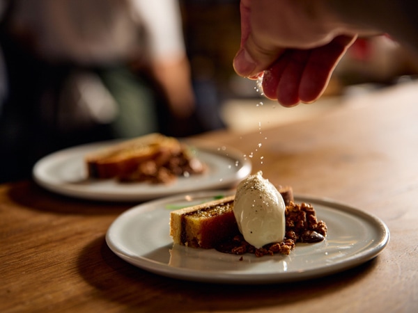 a close-up of hand sprinkling spices onto a dish at Farmer’s Daughters, CBD