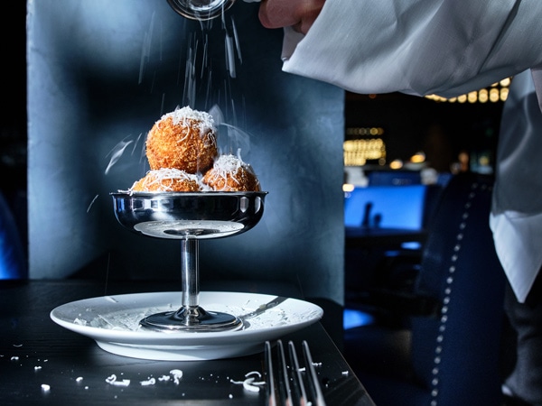 a close-up of Arancini Bolognese topped with cheese at Grill Americano, CBD