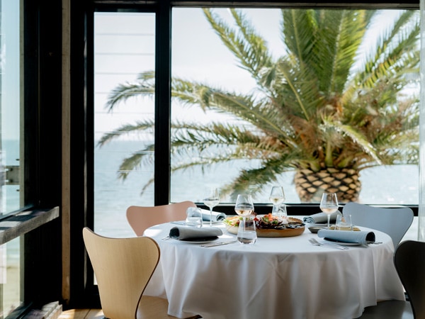 a dining table next to floor-to-ceiling windows at Stokehouse, St Kilda