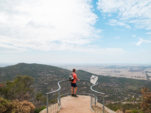 a hiker admiring scenic views on top of You Yangs Regional Park, Flinders Peak Walk