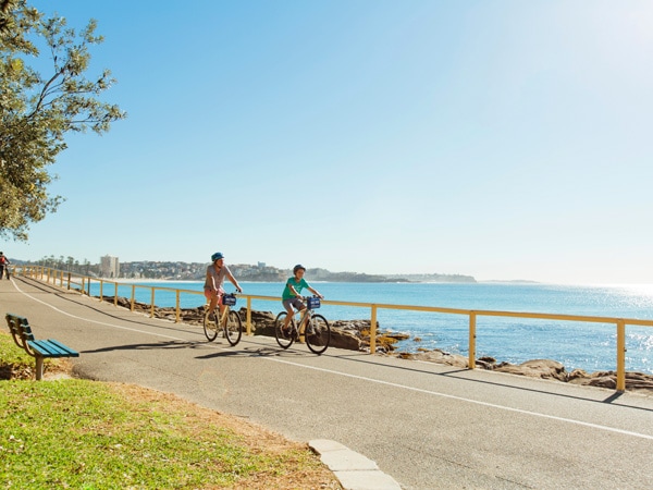 a father and son cycling along Manly Beach