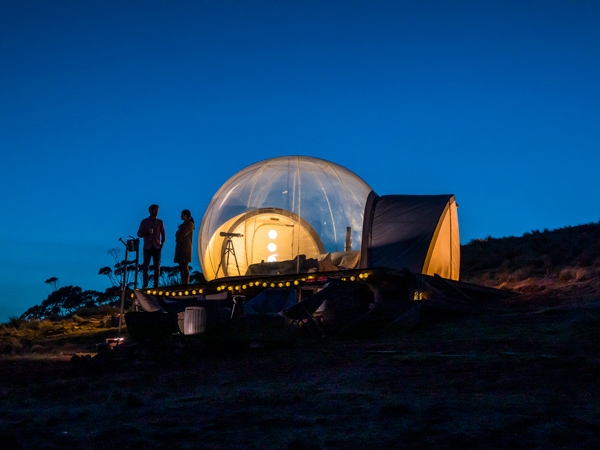 a couple relaxing at Bubbletent Australia at night