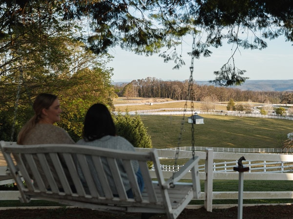 two people sitting on a long bench admiring the landscape at Eden Farm Escape