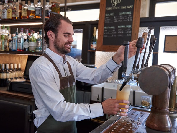 a bartender pouring a glass of beer at the Public House in Hotel Palisade, Millers Point