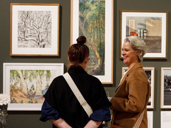 two people talking while browsing through artworks at Manly Art Gallery and Museum