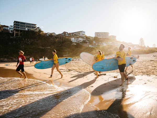 surfers hitting the beach at Manly SurfSchool