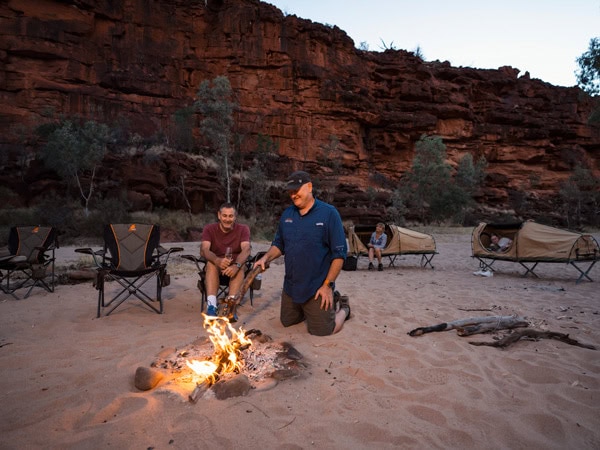 two people sitting in front of a bonfire in a camp, Alice Springs Expeditions