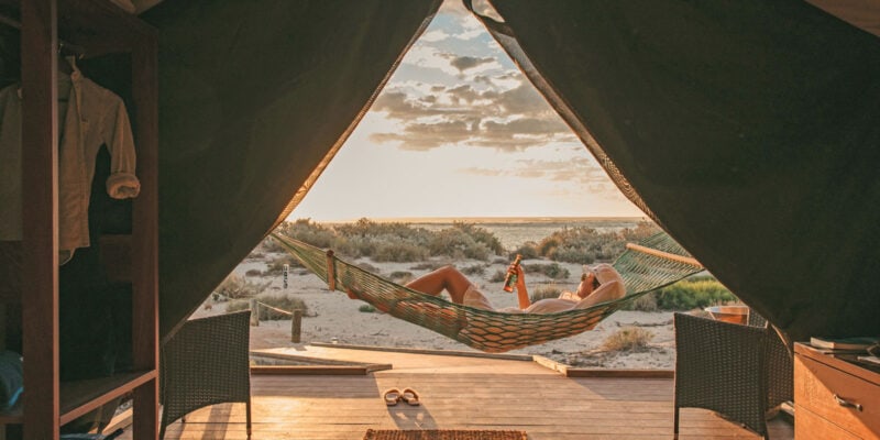 Guest sips a drink in a hammock at Sal Salis as the sun sets