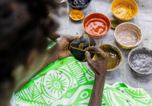 a close-up of a Tiwi artist painting