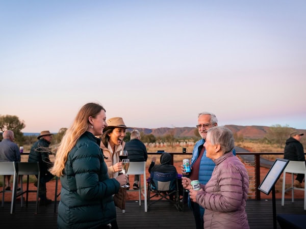 Group gathers at sunset with a wine in hand on an Intrepid tour of the Red Centre