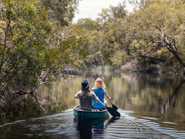 two people riding a boat across Noosa Everglades