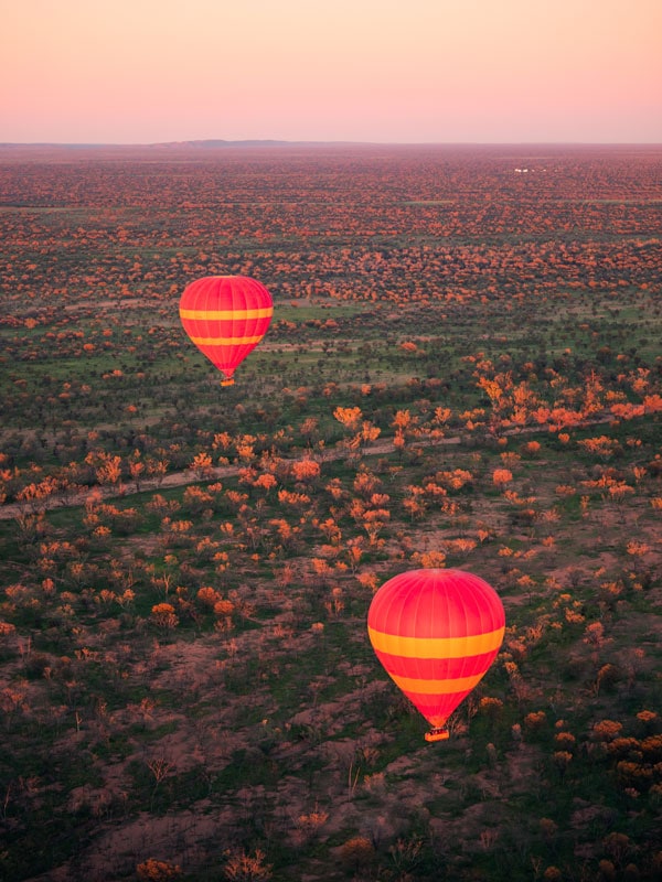 two hot air balloons floating above Alice Springs