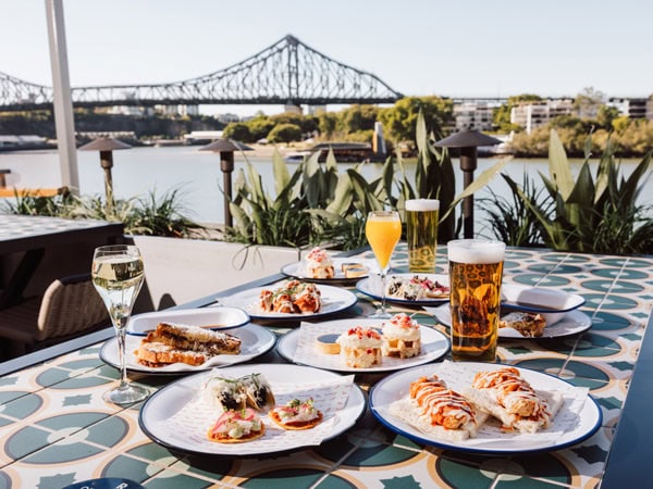 a spread of bottomless brunch on the table next to Brisbane River at Riverland Brisbane
