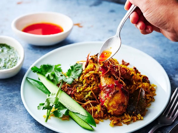 a hand pouring sauce onto a Thai dish at Short Grain, Brisbane