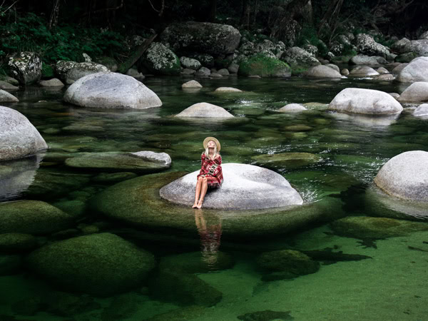 a woman sitting on a huge rock at Mossman Gorge