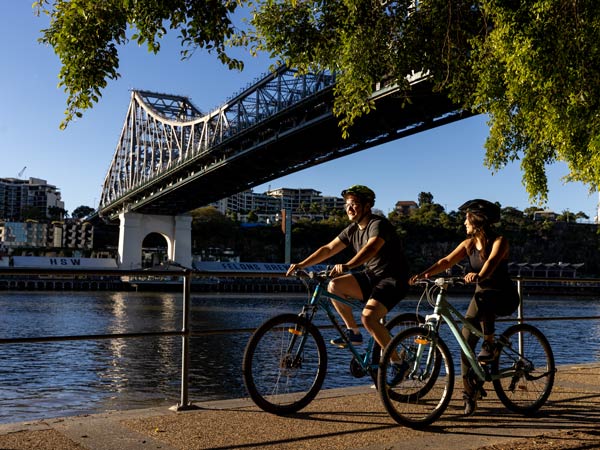 People cycling with Brisbane's Story Bridge in the background