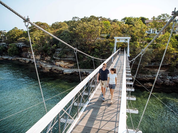 two people walking along a bridge towards Parsley Bay Beach