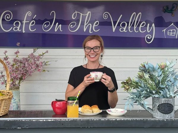a woman smiling while holding a cup of coffee at Cafe In The Valley