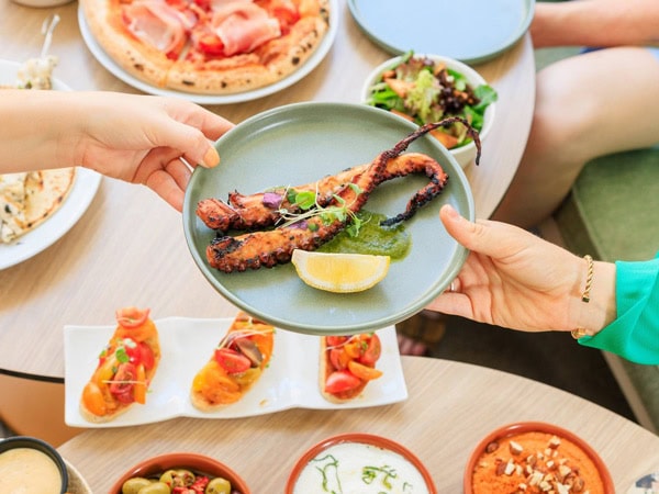 hands holding a plate of food in the middle of the table at Hibiscus Bar & Terrace, Brisbane