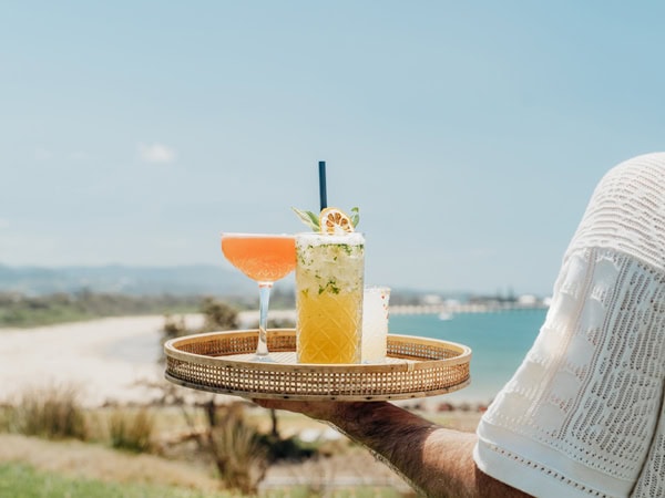 a hand holding drinks at Jetty Beach House