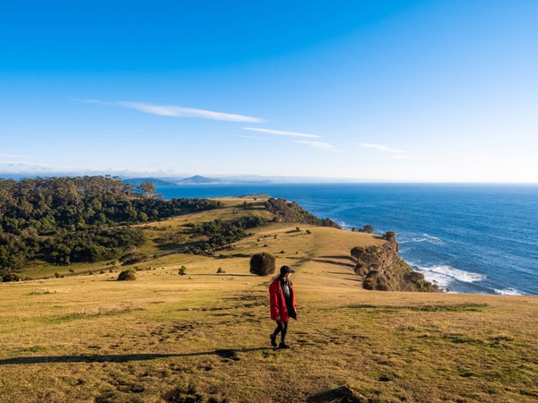 a woman standing on top of a cliff with views of the sea on Maria Island