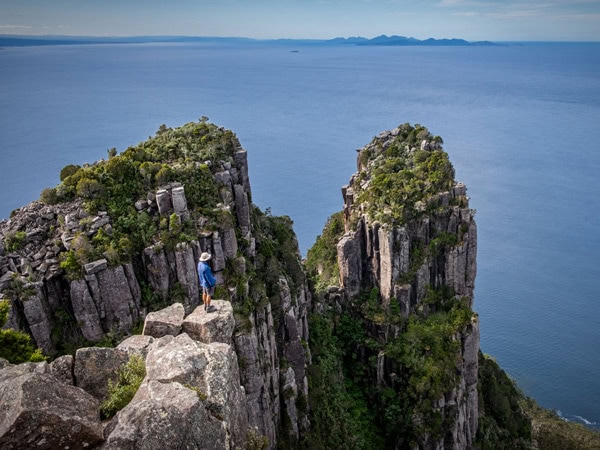 a man standing on top of Bishop and Clerk on Maria Island