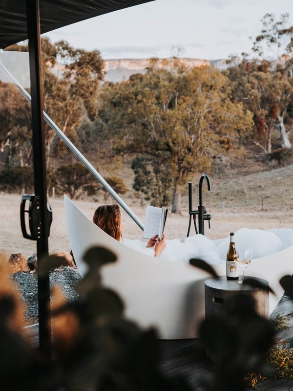 a woman relaxing in the tub while reading a book at Wildnest Farmstay